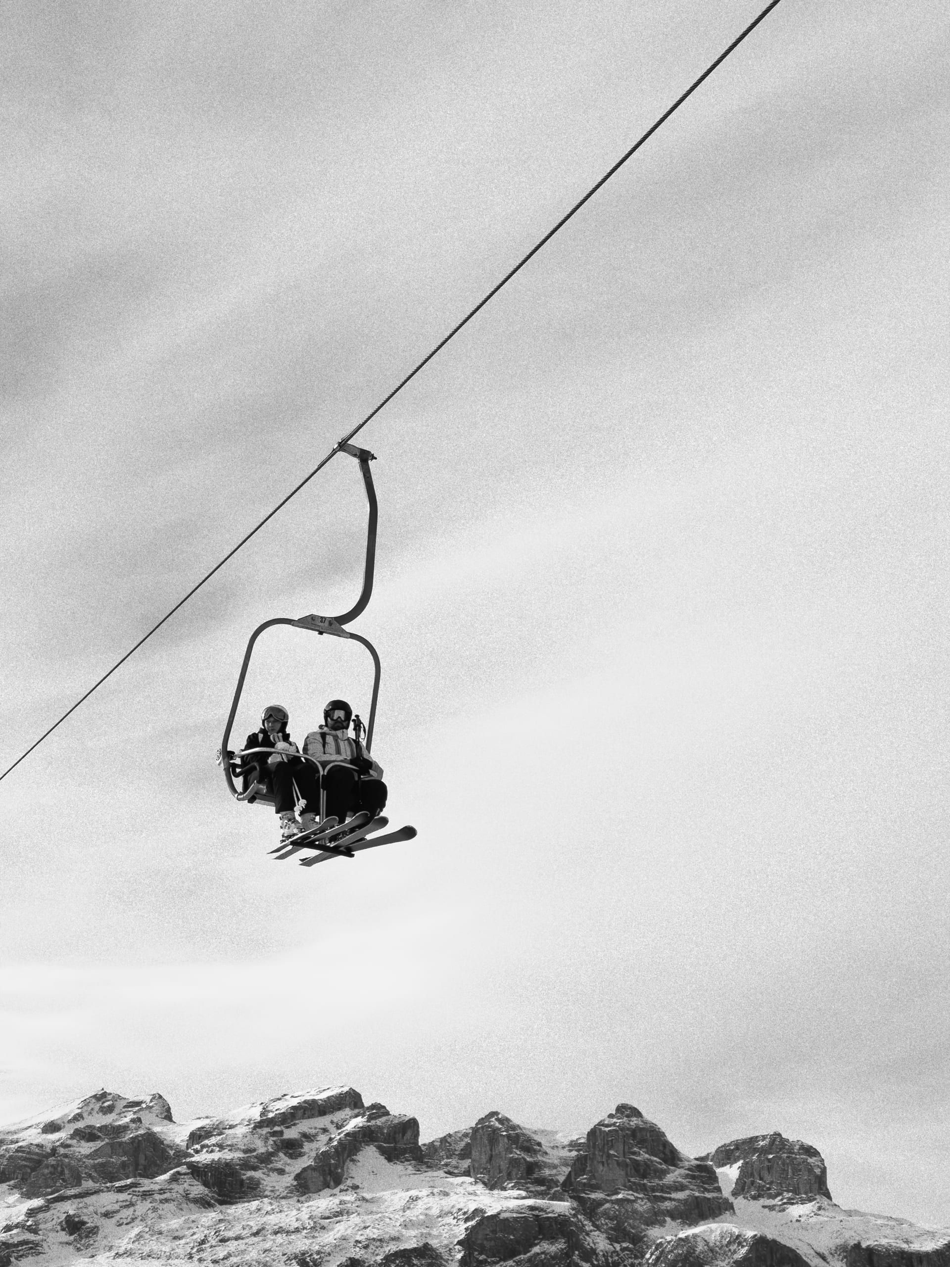Two riders on the lift in Dolomiti.